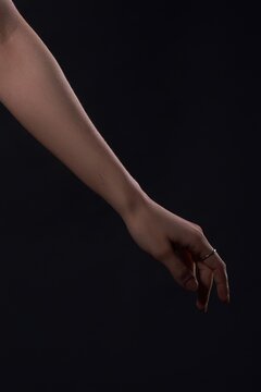 Elegant woman's arm and hand with rim lighting against a black background