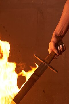 Close-up of a female warrior's hand holding a flaming sword