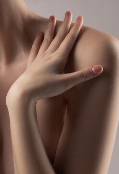 Intimate close-up of a woman's gentle hand on her bare shoulder.