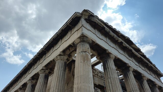 Athens, Greece - 8 July 2026. Corner view of the Temple of Hephaestus in the Ancient Agora, with Doric Marble - Rock columns, pediment, entablature, inner frieze, scaffolding, and Overcast sky.