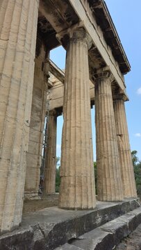 Athens, Greece - 8 July 2026. Side view of the Temple of Hephaestus in the Ancient Agora, with Doric Marble - Rock columns, entablature, stone material steps, scaffolding, and sky.