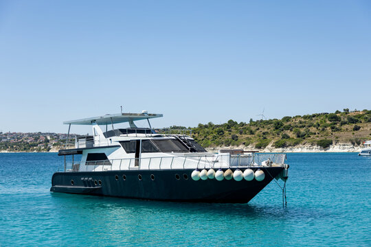 Luxury yacht anchored on turquoise sea near island coast