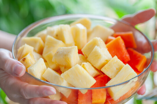 Fresh tropical fruit salad with juicy pineapple and ripe papaya cubes served in a glass bowl. Colorful healthy snack rich in vitamins, digestive enzymes and natural antioxidants for balanced nutrition