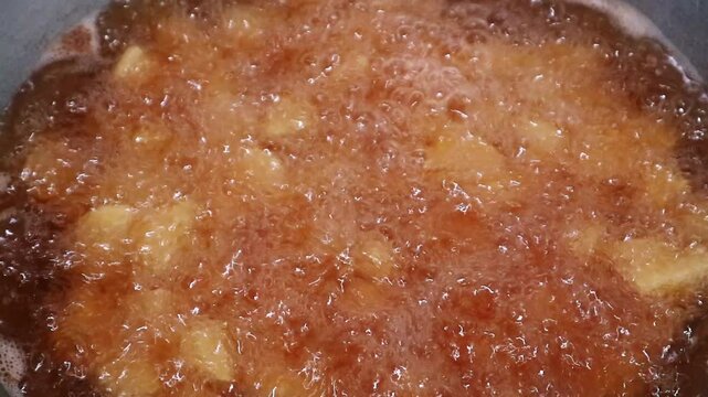 Close up of delicious apple pieces simmering in a sweet caramel sauce in a pan.