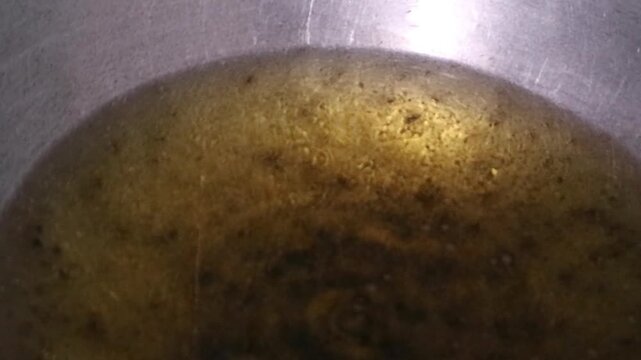 Close up view of hot cooking oil in a metal pan for frying food.
