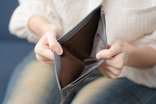 Financial hardship concept. Person showing an empty wallet at home, symbolizing money shortage, debt and personal budget stress. Empty wallet, finance, debt, poverty, budget.