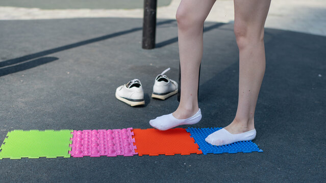A woman with cerebral palsy walks on sensory mats. Rehabilitation