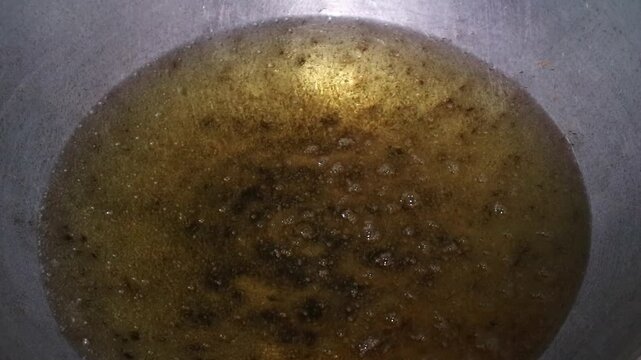 Hot cooking oil bubbling in a metal pan for deep frying.
