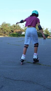 Girl inline skating in safety gear across a park at golden hour