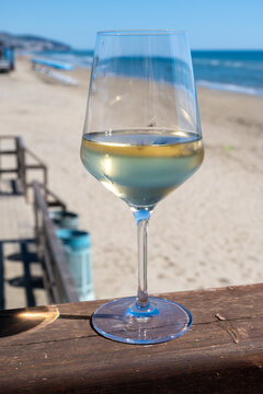 Chilled glass of white wine and sandy beach near Sperlonga, Italy, relaxed seaside holiday atmosphere near popular coastal resort town