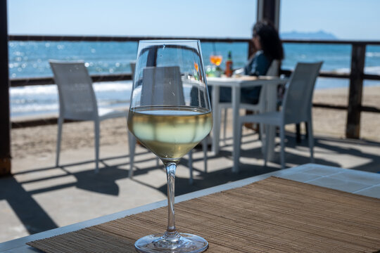 Chilled glass of white wine and sandy beach near Sperlonga, Italy, relaxed seaside holiday atmosphere near popular coastal resort town
