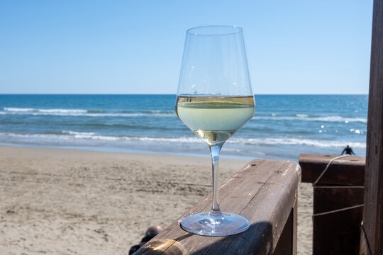 Chilled glass of white wine and sandy beach near Sperlonga, Italy, relaxed seaside holiday atmosphere near popular coastal resort town