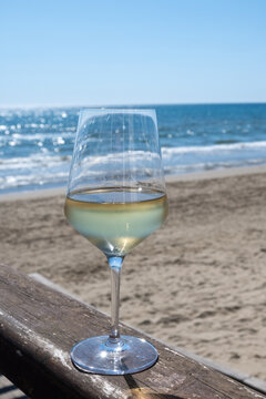 Chilled glass of white wine and sandy beach near Sperlonga, Italy, relaxed seaside holiday atmosphere near popular coastal resort town
