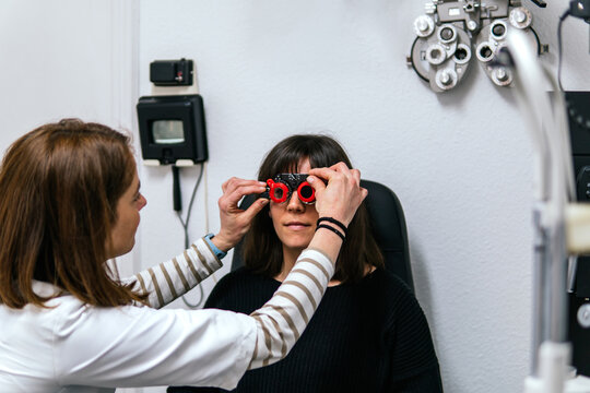 Optician fit trial frame for woman during eye exam