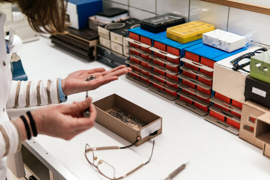 Woman sort optical screws at eyewear repair workstation