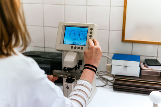 Woman operate optical lens analyzer in optician laboratory