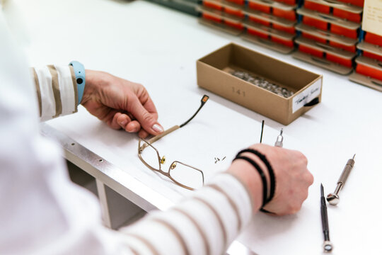 Woman optician repair eyeglass frame at workbench