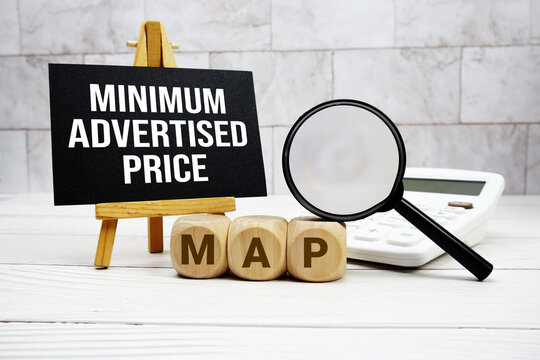 MAP Minimum Advertised Price text with calculator magnifying glass and on wooden background