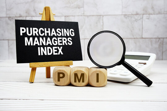 PMI Purchasing Managers Index text with calculator magnifying glass and on wooden background
