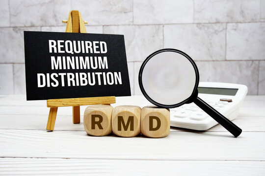 RMD Required Minimum Distribution text with calculator magnifying glass and on wooden background