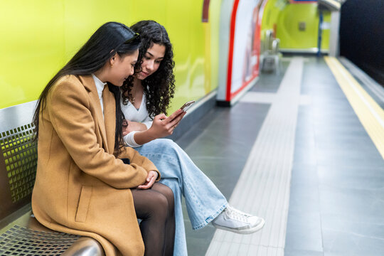 Friends enjoy smartphone at Madrid metro station platform
