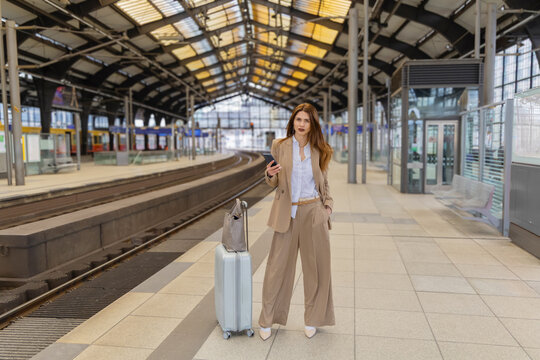 Businesswoman with suitcase at train station platform