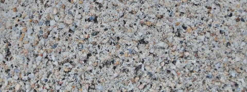 Coarse concrete texture with exposed aggregate, rough cement surface with small grey pebbles, industrial construction material background