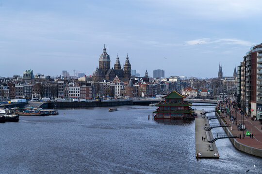 Moored passenger boats, houseboats, and historic drawbridge on Amstel river in Amsterdam