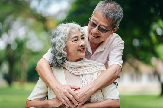 Elderly couple embracing lovingly outdoors park showing deep aff