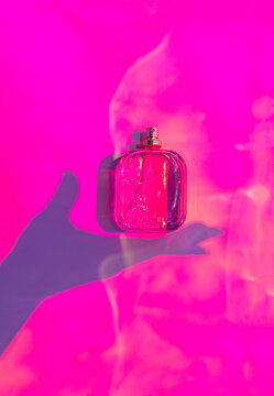 Pink perfume bottle mockup with hand shadow and mist