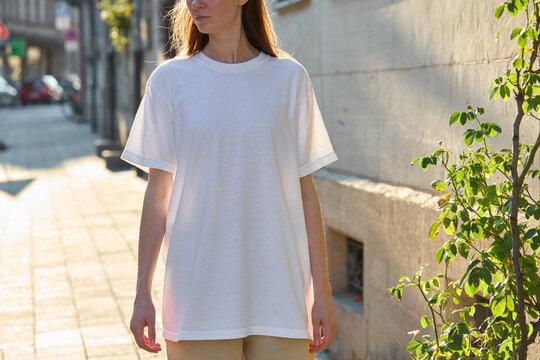 Woman wearing a plain white t-shirt and beige pants on a sunny street
