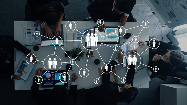 A diverse group of professionals collaborates on data analysis in a modern office, utilizing digital interfaces to foster innovation, strategy, and teamwork through visual networking. Ledger