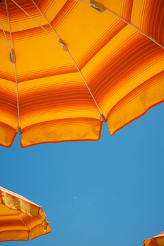 Orange beach umbrellas against blue sky in sicily, italy