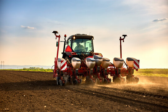 Farmer driving tractor seeding fields, cultivating land during agricultural season