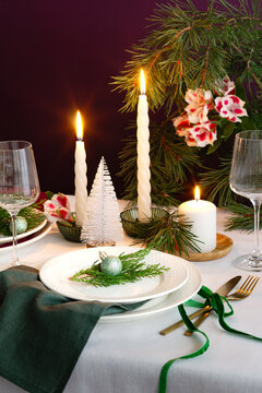 Christmas table setting with candles, evergreen and ornament
