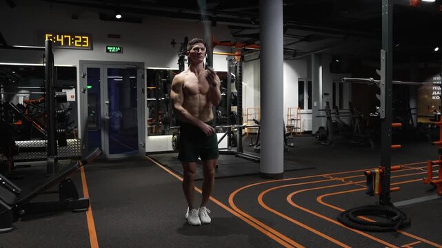 sport and fitness. athlete man exercising in gym. athletic guy exercising with jumping rope. fit and active sportsman skipping rope. sportsman working out on a skipping rope in gym. cardiovascular