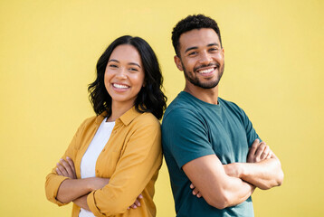 Obraz premium Confident young man and woman standing back to back with crossed arms on a yellow background
