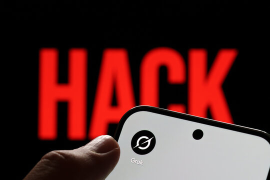 Grok app logo shown on a smartphone held in hand against a red HACK warning in an AI security concept. Stafford, United Kingdom, August 2, 2026.