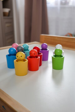 Colorful Montessori color sorting toy with wooden figures arranged on a children's table in a modern playroom.