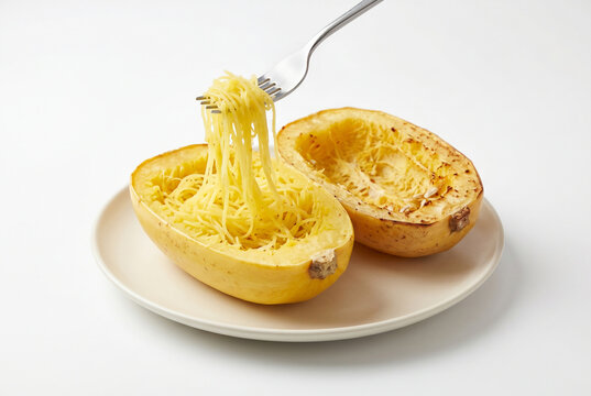 Spaghetti squash halves with fork lifting strands on white plate
