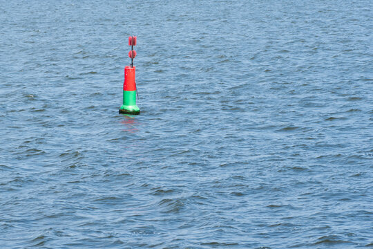 Red and green navigation buoy floating on the rippled blue water of Lake Veluwemeer near Harderwijk, the Netherlands.