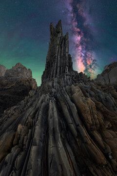 Milky Way above jagged rock spire in dark sky night