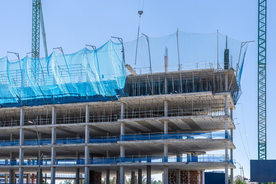 High-rise building construction with blue safety net and crane