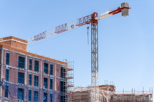 Tower crane beside unfinished brick building under blue sky
