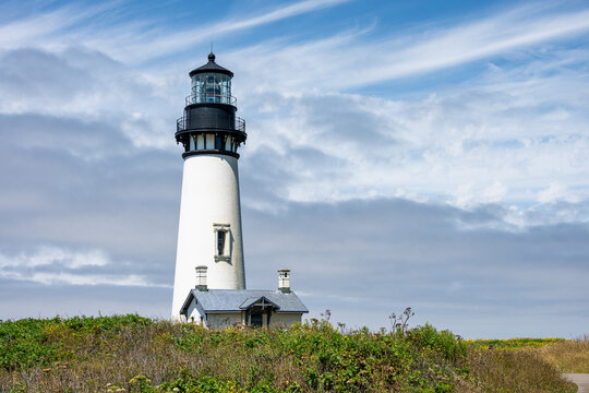 Lighthouse on the headland at Yaquina Head Outstanding Natural Area, cloudy sky in background, summer vacation road trip on the Oregon Coast
