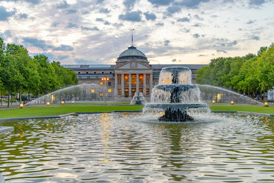 view at bowling green to kurhaus and casino  in Wiesbaden with fountain in foreground and dramatic sunrise sky