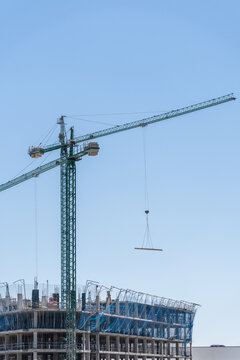 Tower crane above unfinished concrete building under blue sky