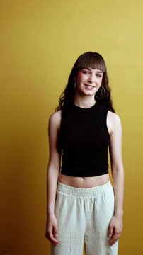 Confident young woman with bangs smiling on a yellow background