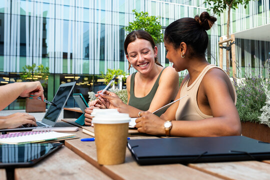 University students collaborating outdoors using laptop and tablet