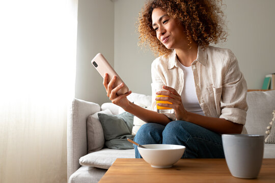 Young woman relaxing on sofa using smartphone